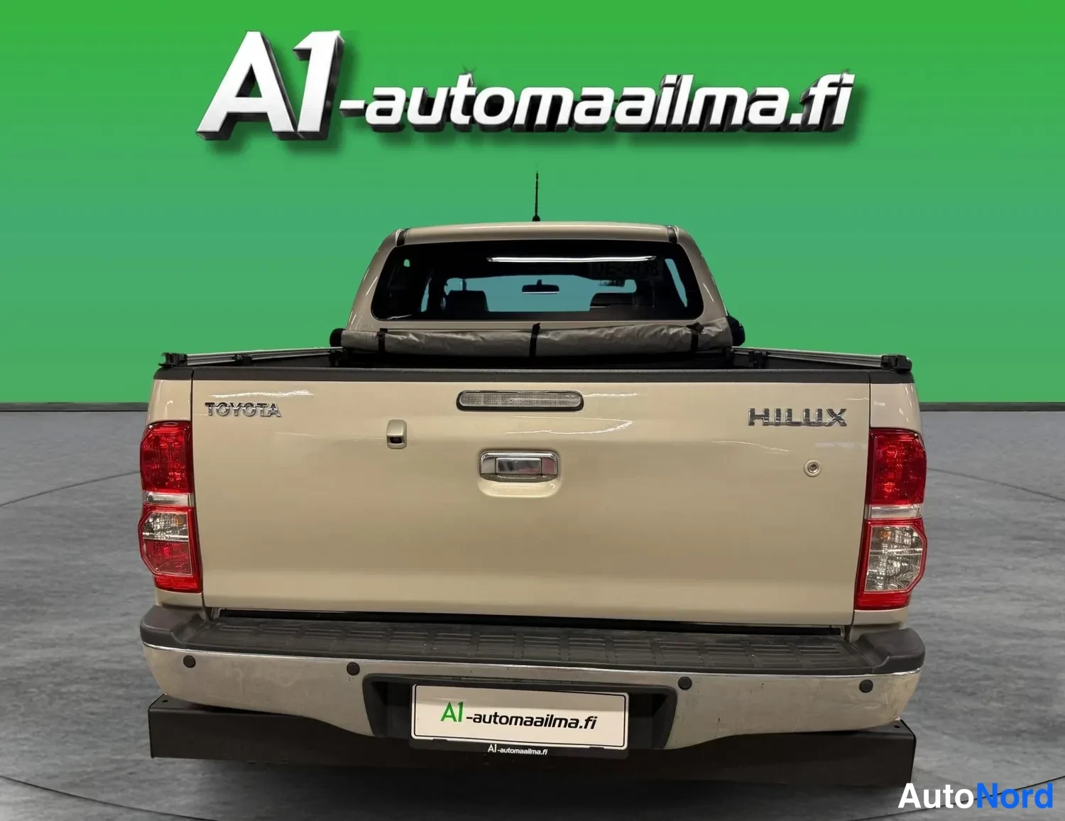 Takaa: Kultaisen pickupin peräsuora takaa; peräportissa TOYOTA- ja HILUX-tekstit ja punaiset takavalot.