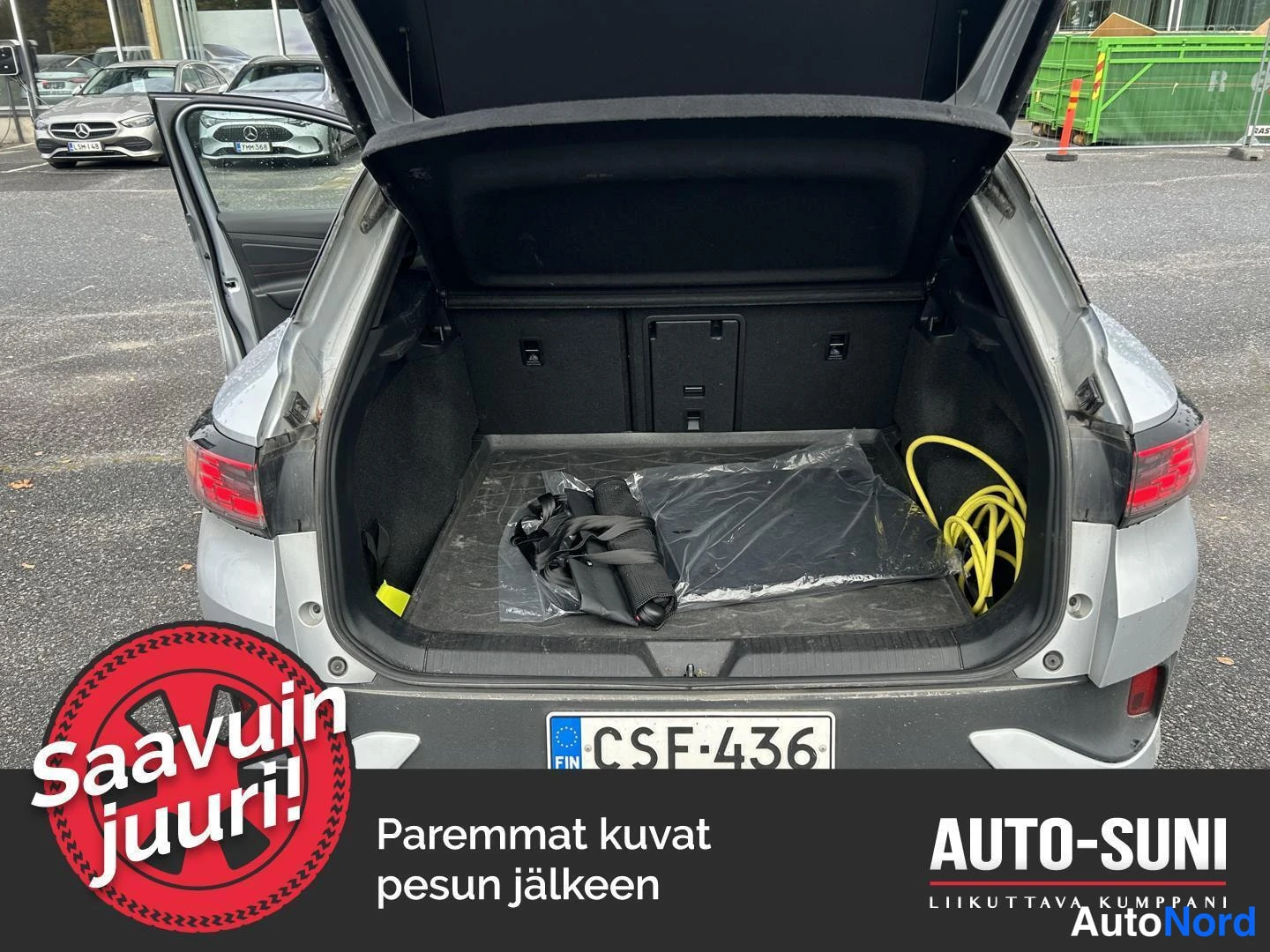 Takaa: Avatun takaluukin takatila muovipussissa olevine tarvikkeineen ja keltaineen latauskaapelineen; rekisterikilpi, kori hopeanvärinen.