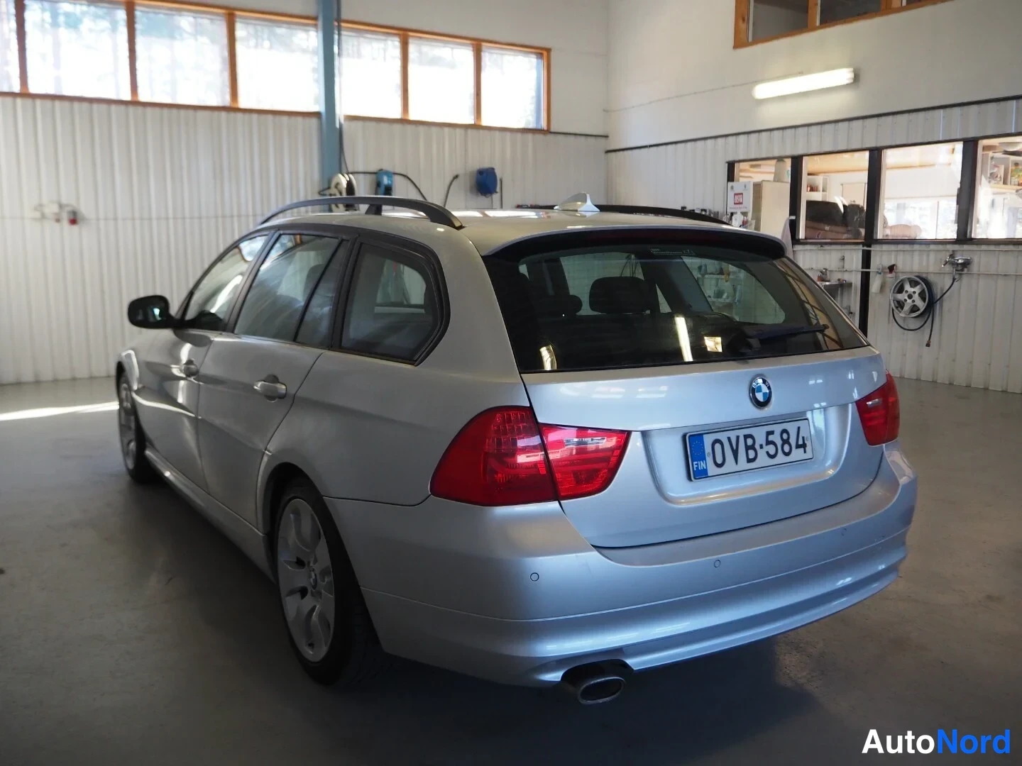 Takaviisto: BMW 318d Touring -farmari, takakulmasta vasemmalta korjaamotiloissa, rekisteritunnus.