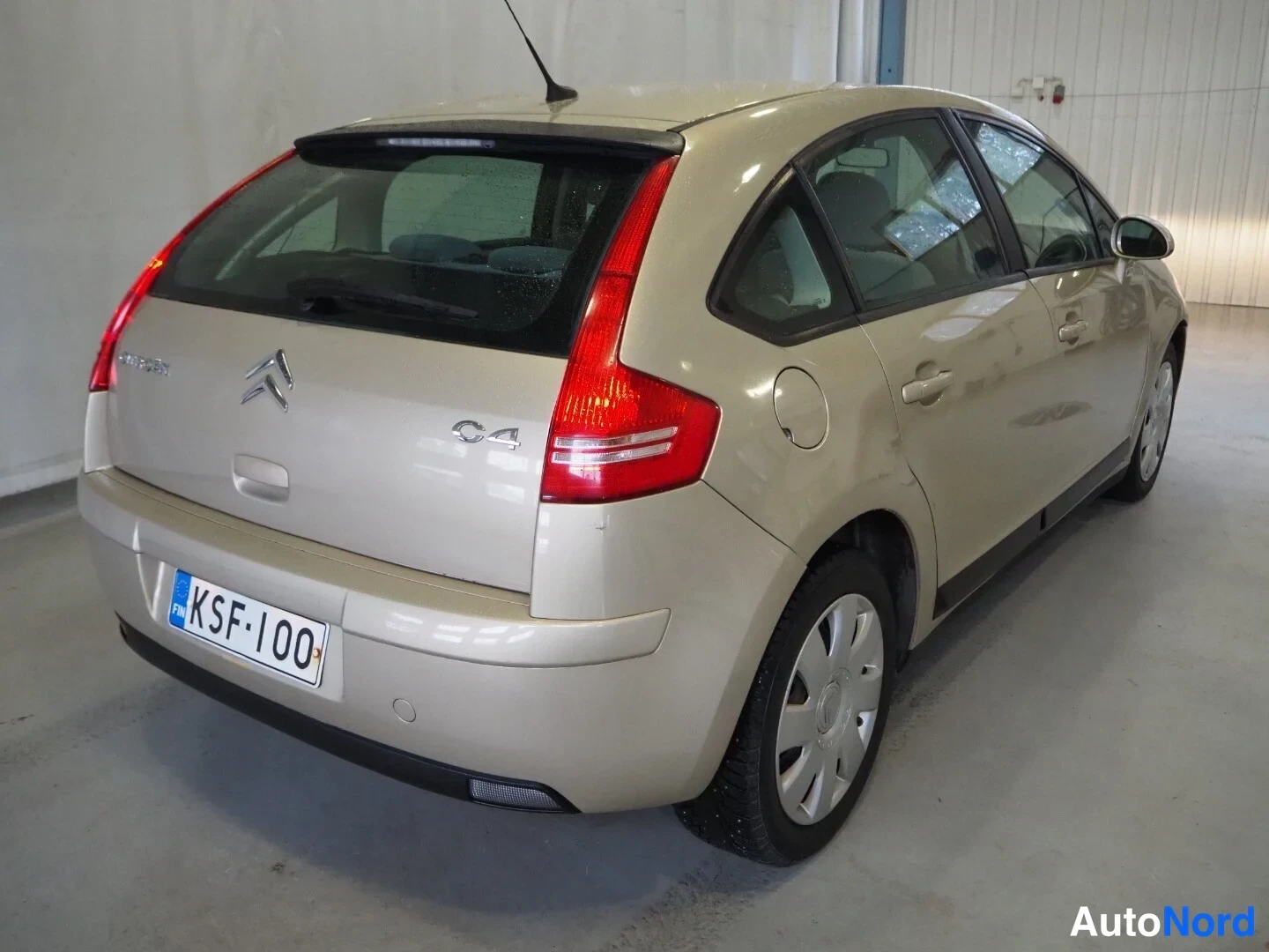 Takaviisto: Taka­kolmasel näkymä kulta­vaaleasta Citroën C4 -autista; taka­valot ja rekisterikilpi näkyvät.