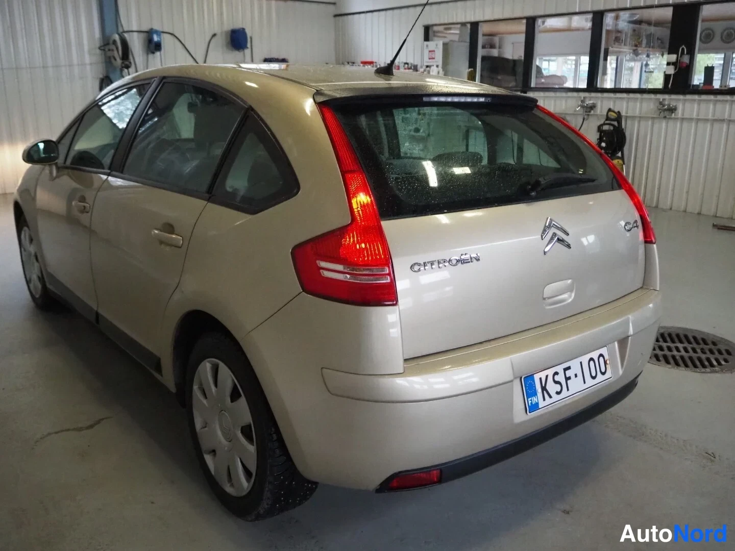 Takaviisto: Taka­kolmasel näkymä kulta­vaaleasta Citroën C4 -autista varikolla; rekisterikilpi näkyvät.