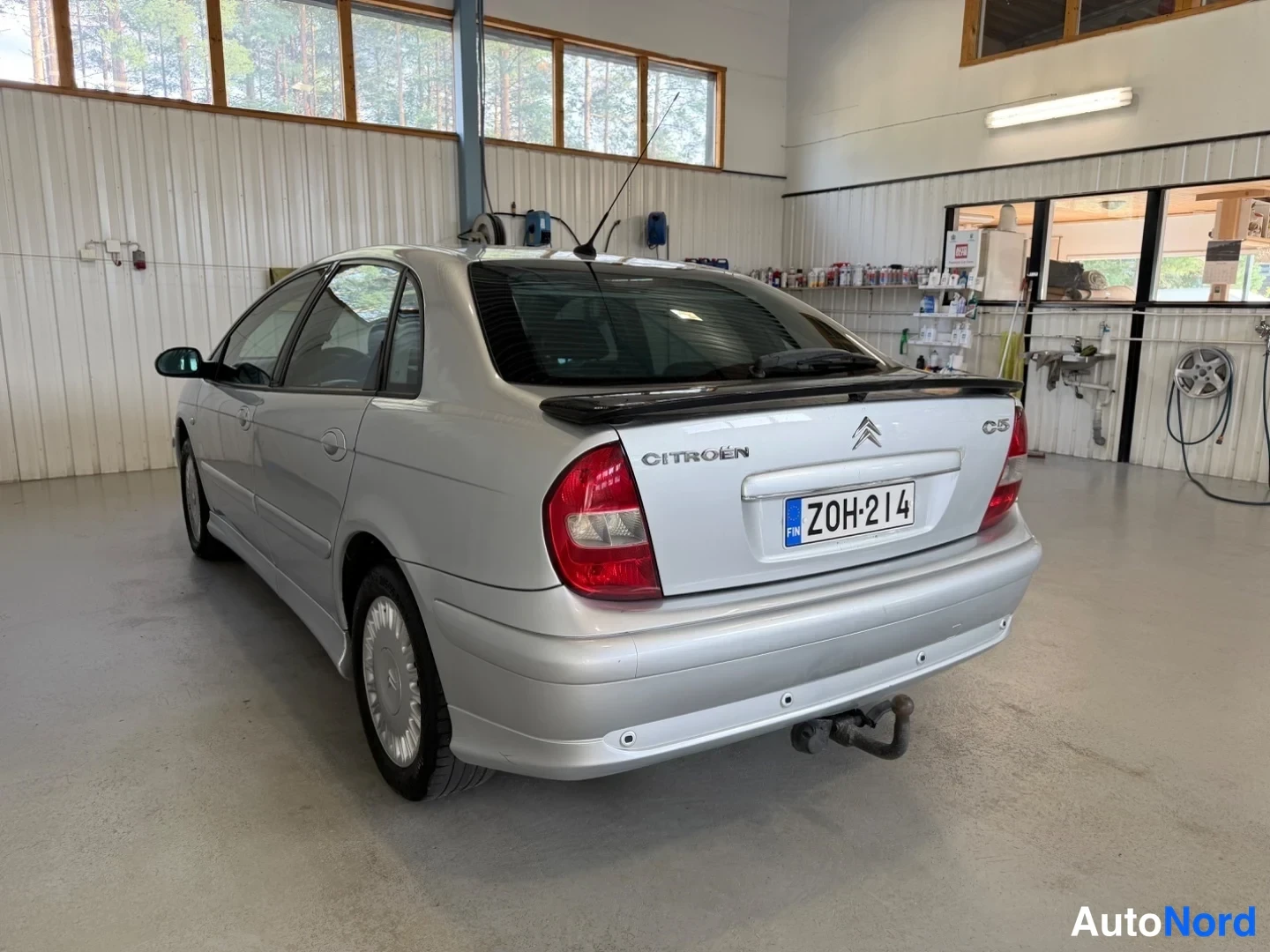 Takaviisto: Hopeanvärinen sedan takakulmasta huoltamossa, takaluukussa Citroën- ja C5-tekstit.
