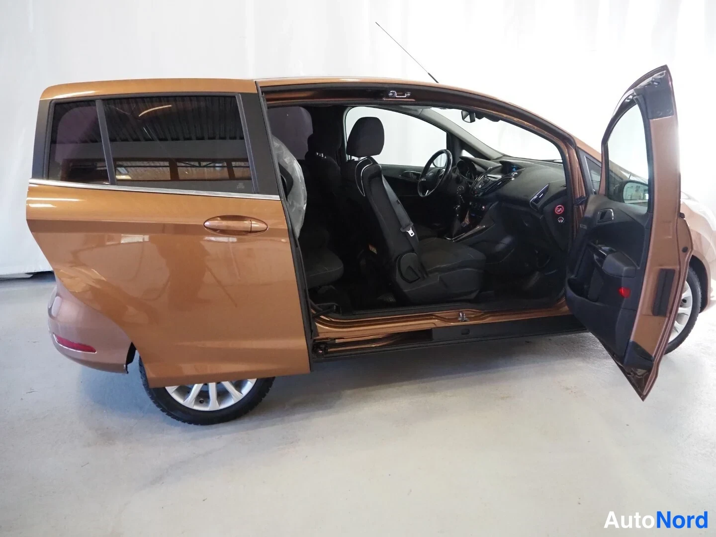 Sivulta: Ford B-Max sivulta vasemmalta, takaovi ja vetiovi auki, tumma sisustus ja etuistuimet näkyvät.