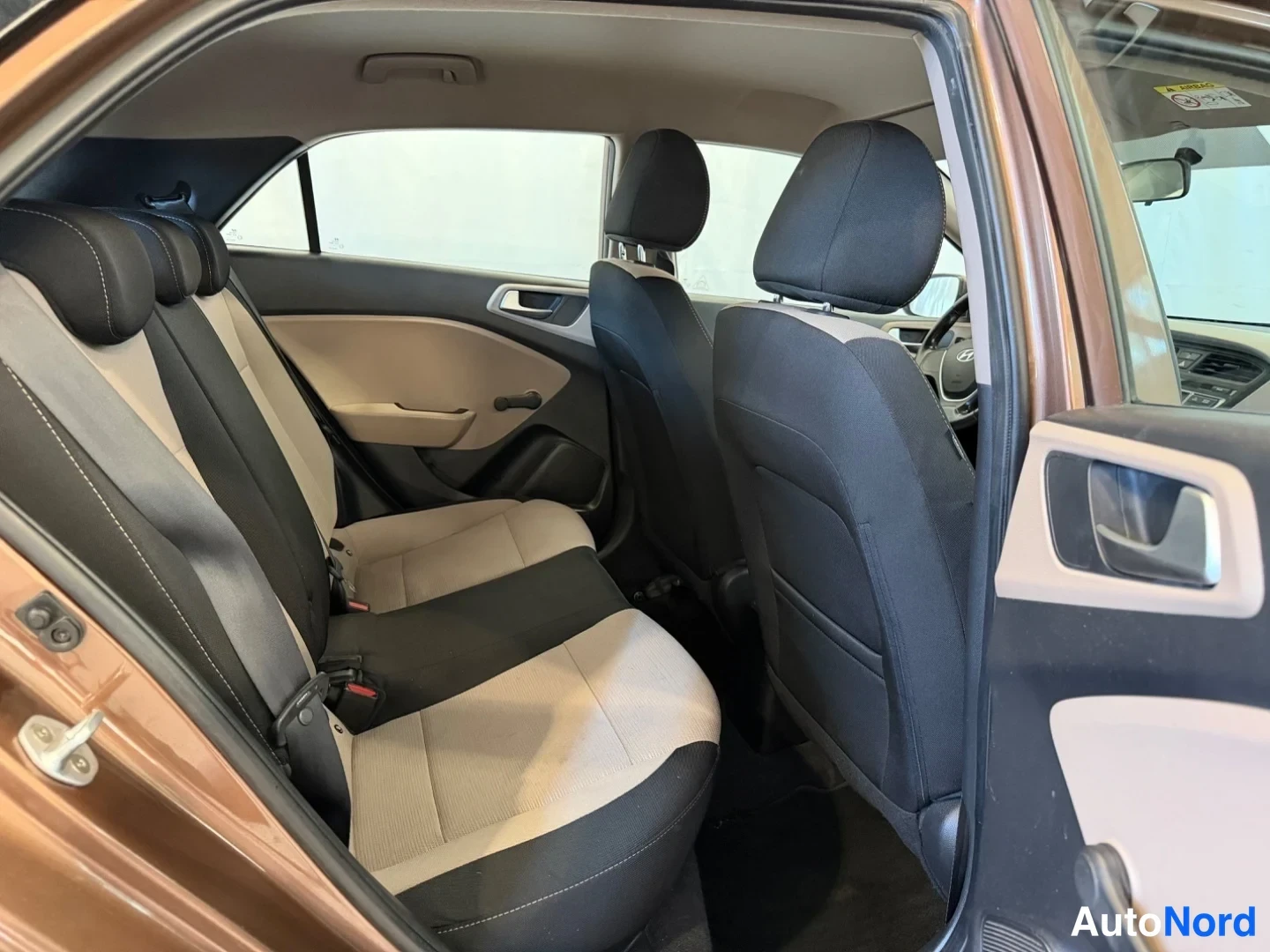 Muu: Hyundai i20:n takasomatila vasemmalta takovenestä kuvattuna, taitettava takaselkänoja ja beige-mustat istuimet.