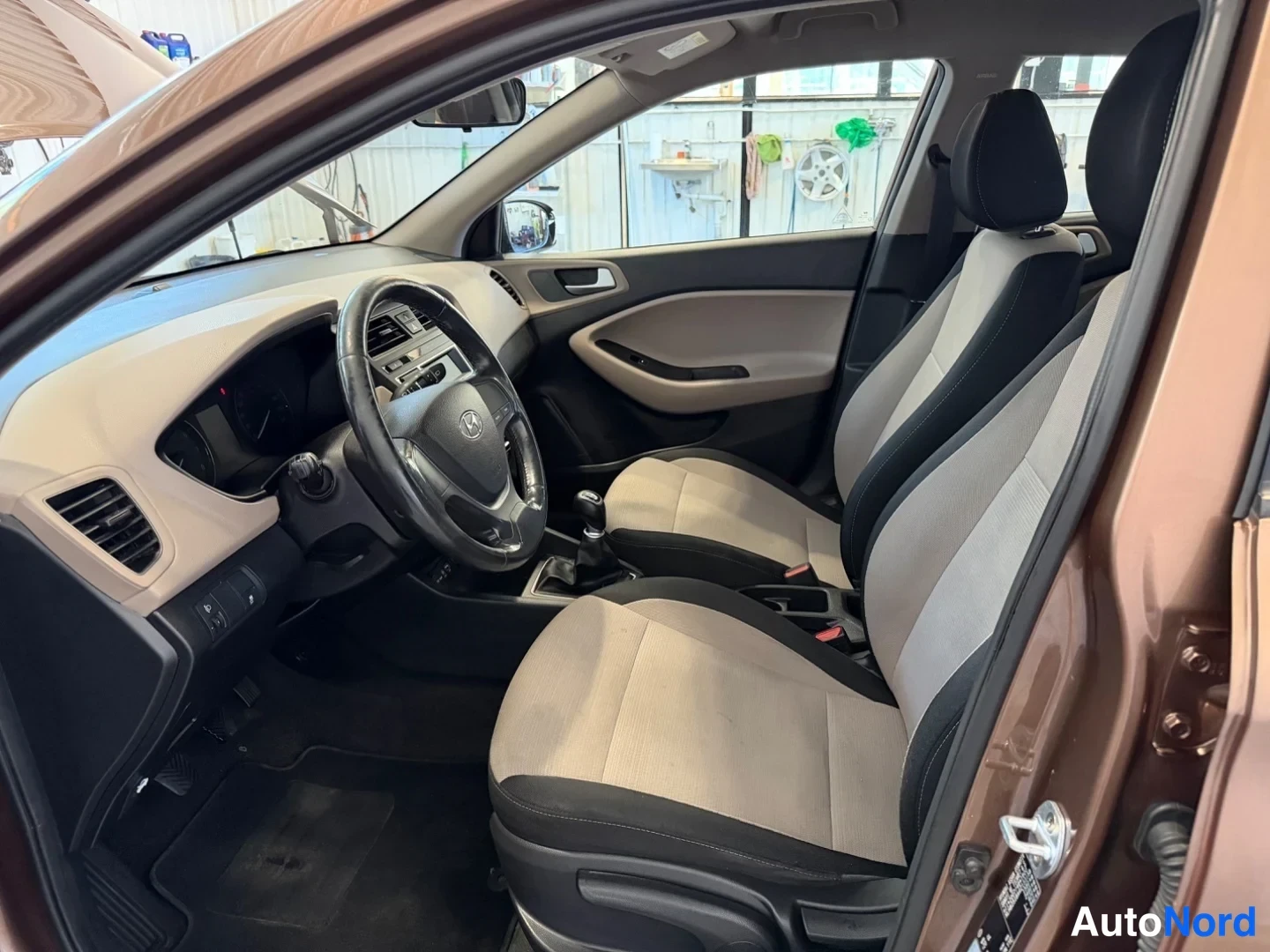 Sivulta: Näkymä Hyundai i20:n etuistuimelta kohti etuosaa: Honda-merkitty ... ohjauspyörä puuttuu, kuvassa Hyundai-ohjauspyörä, manuaalivaihtoheijastin ja kaksiväriset i