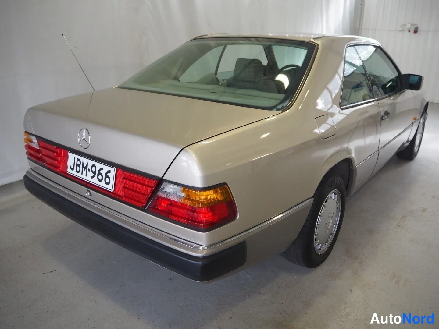 Takaviisto: Mercedes-Benz-kupé takaa vasemmalta kolmivartalokuva, kultainen runko, rekisteri.