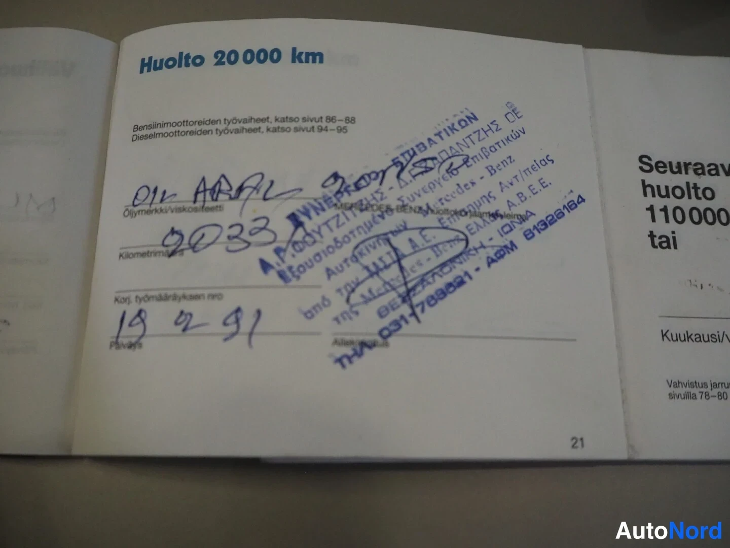Yksityiskohta: Huoltokirjan sivu 21: Huolto 20 000 km, käsinkirjoitettuja merkintöjä ja sininen leima.