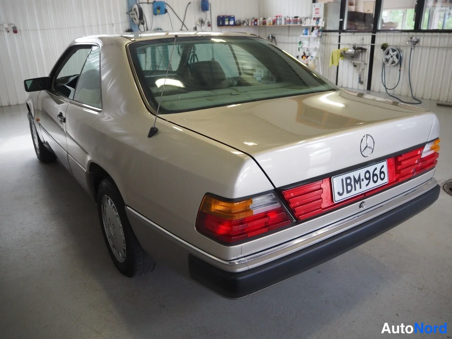 Takaviisto: Mercedes-Benz-kupé takaa oikealta kolmivartalokuva, kultainen runko, rekisteri.