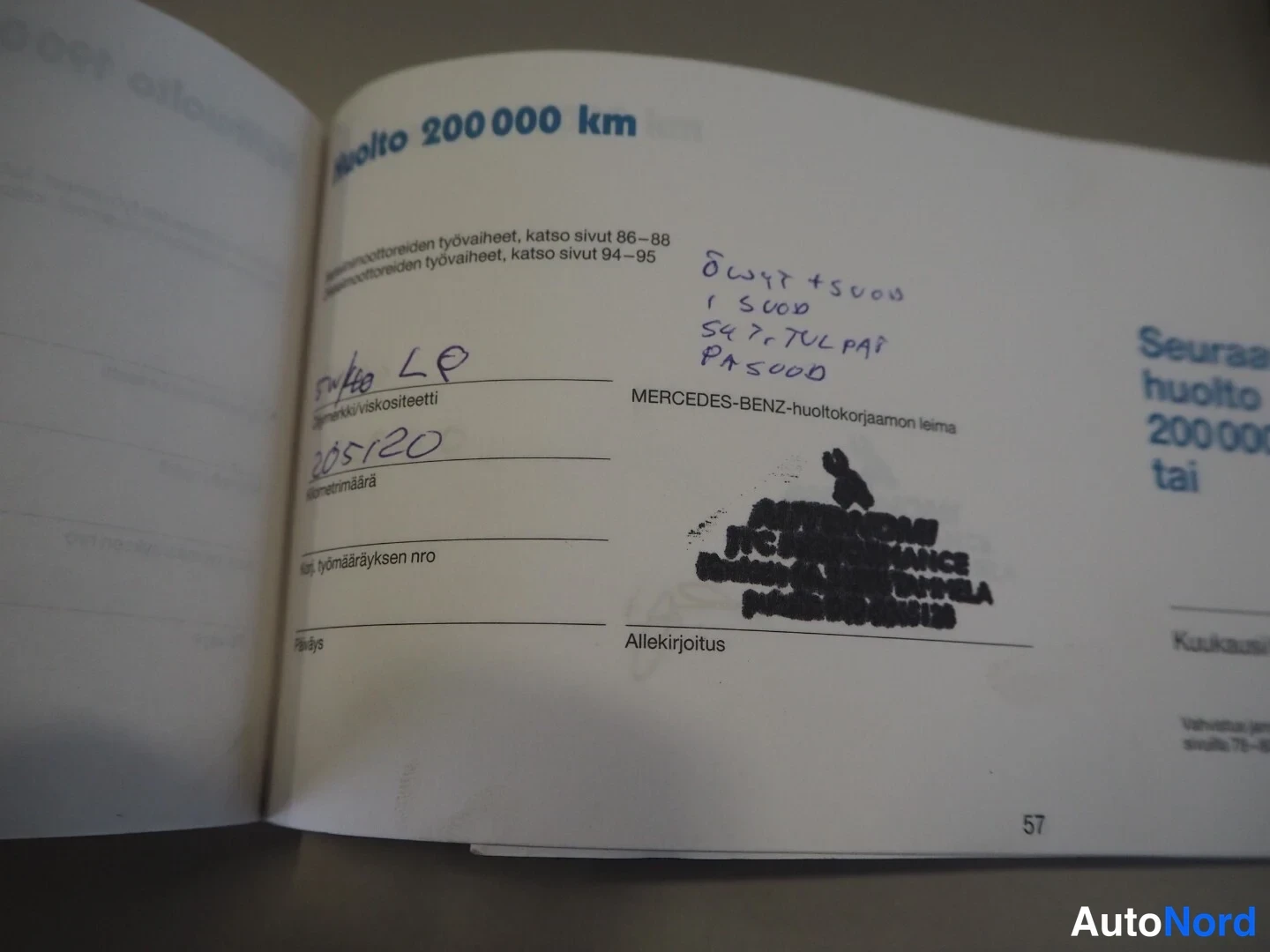 Muu: Huoltokirjan sivu 57: huolto 200 000 km, käsin kirjoitettuja merkintöjä ja epäselvä musta leima.