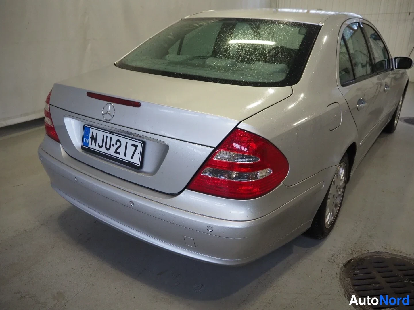 Takaviisto: Hopeinen Mercedes-Benz sedan takaviistöstä vasemmalta, rekisteritunnus.