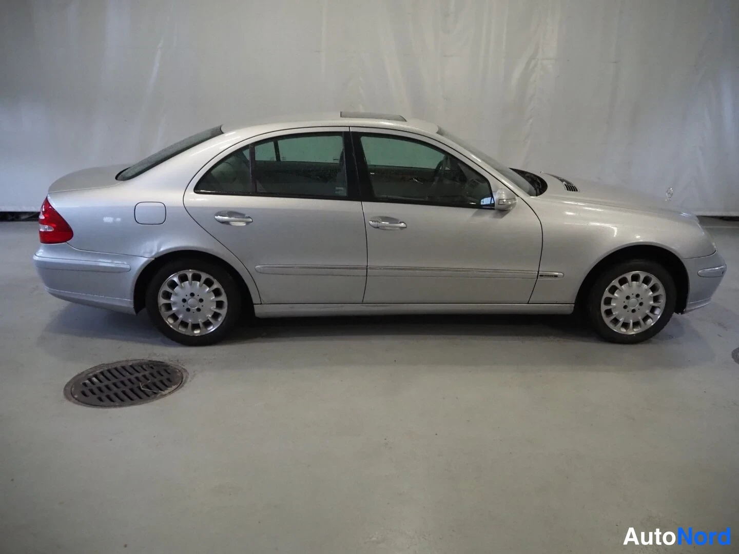 Sivulta: Hopeisen Mercedes-Benz sedans sivuprofiili sisätiloissa.