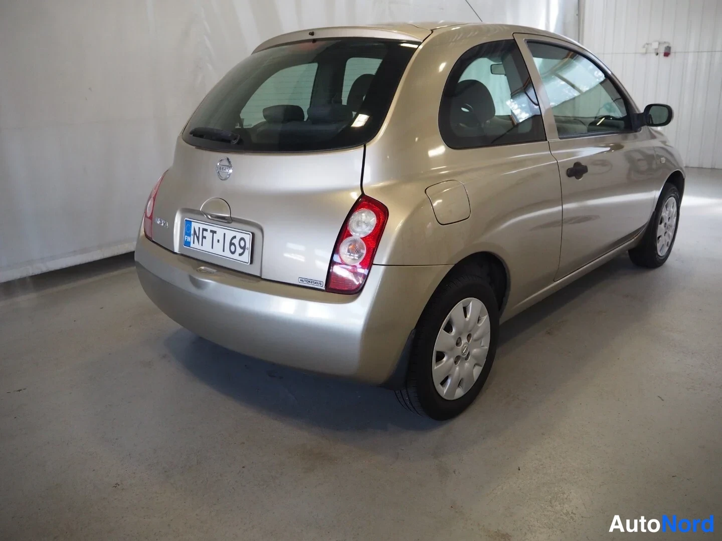 Takaviisto: Kultaisen killisen Nissan Micra -henkilöauton takaosa vasemmalta valokuvattuna autotallissa.