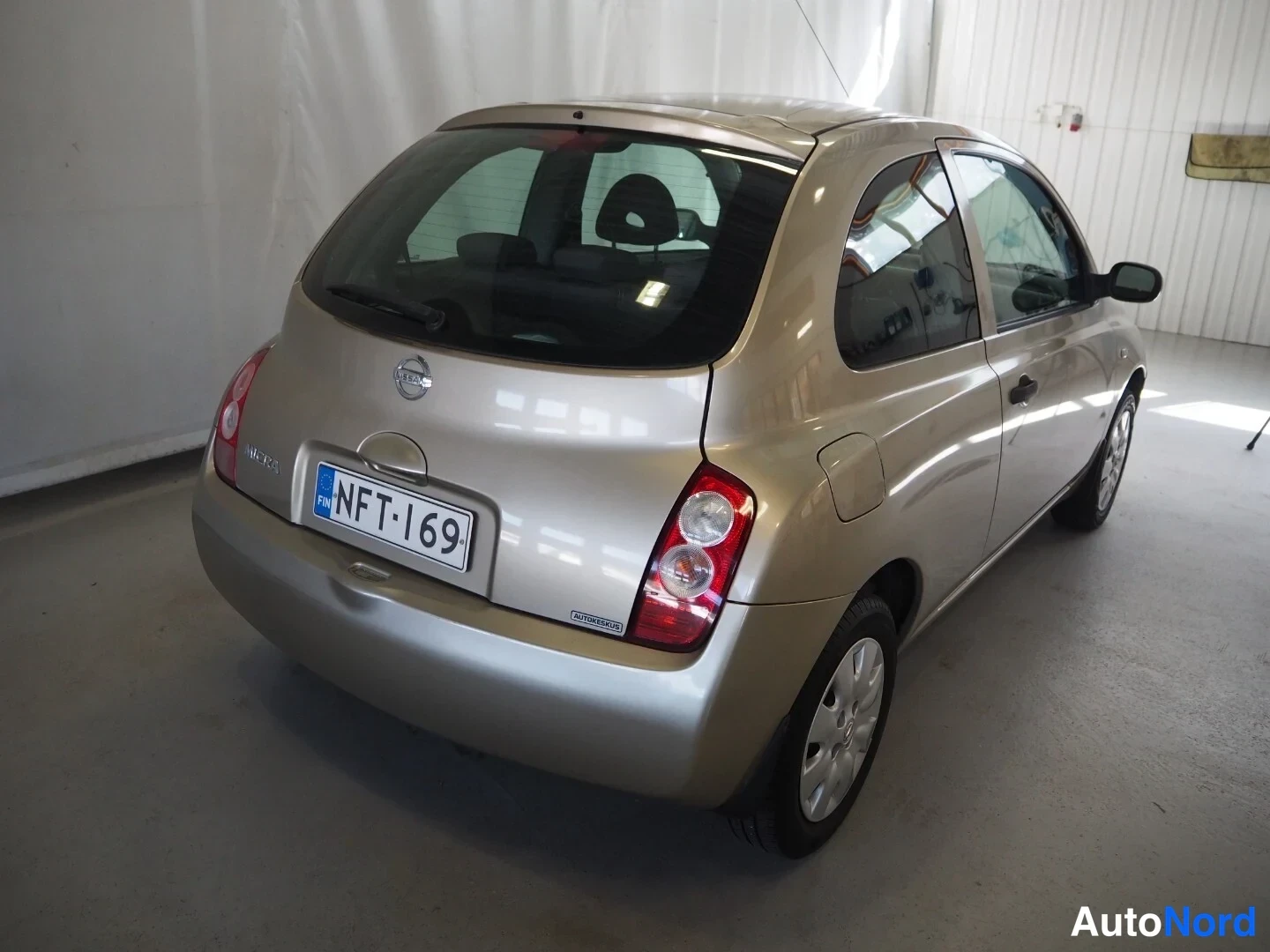 Takaviisto: Nissan Micra -auton takakulma oikealta; takaosan mutka, takavalot ja rekisteri näkyvät selvästi.