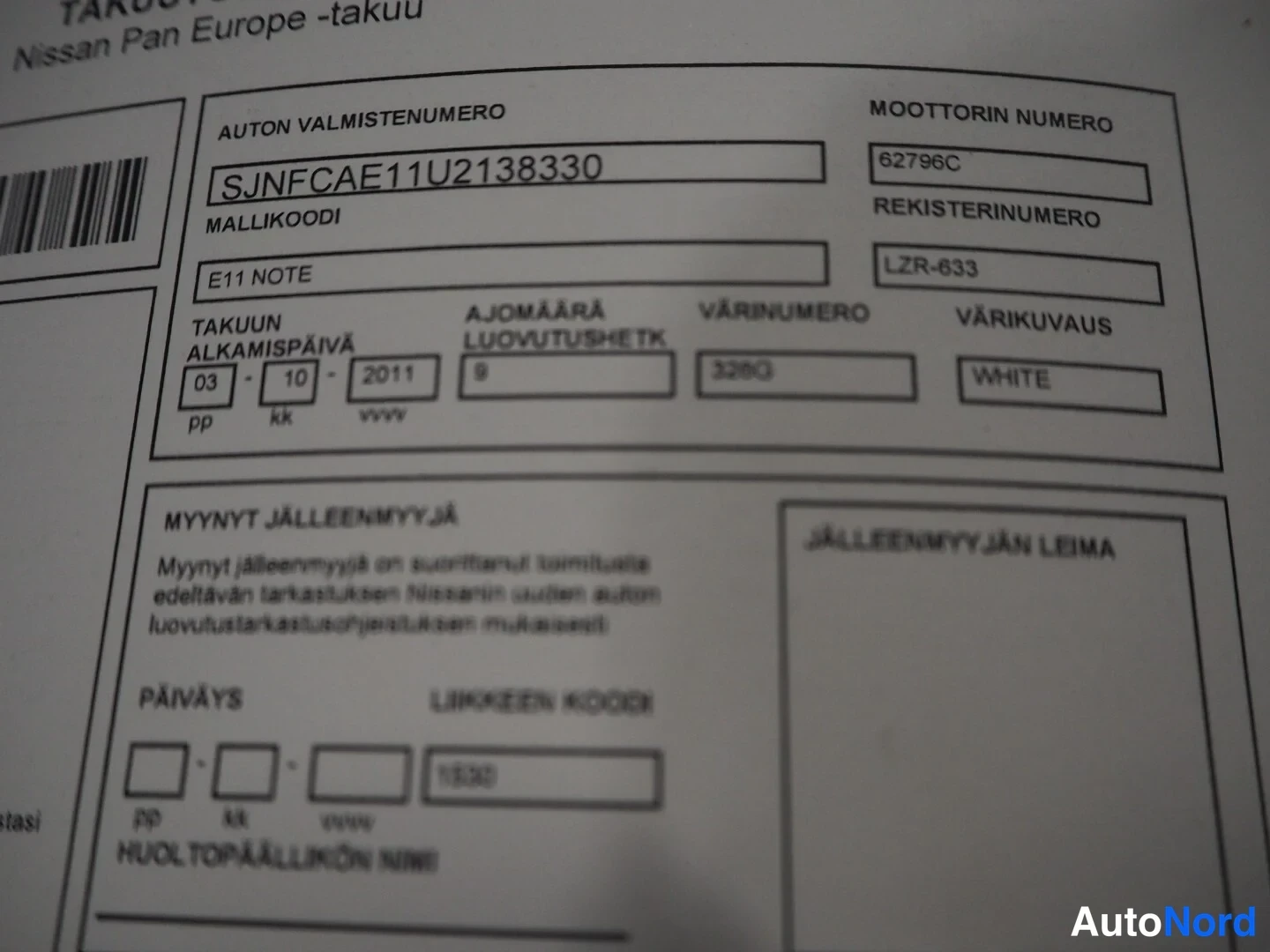 Yksityiskohta: Nissan Pan Europe -takuukirjan sivu, jossa auton valmistenumero SJNFCAE11U2138330 ja rekisterinumero.
