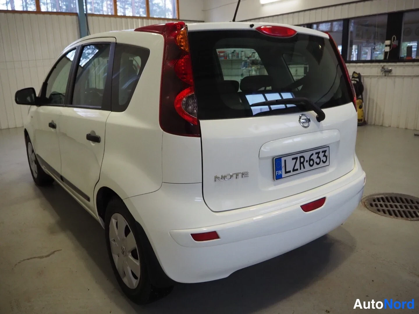 Takaviisto: Valkoisen Nissan Noten takanäkymä vasemmalta, takaluukussa NOTE-teksti ja rekisteritunnus.