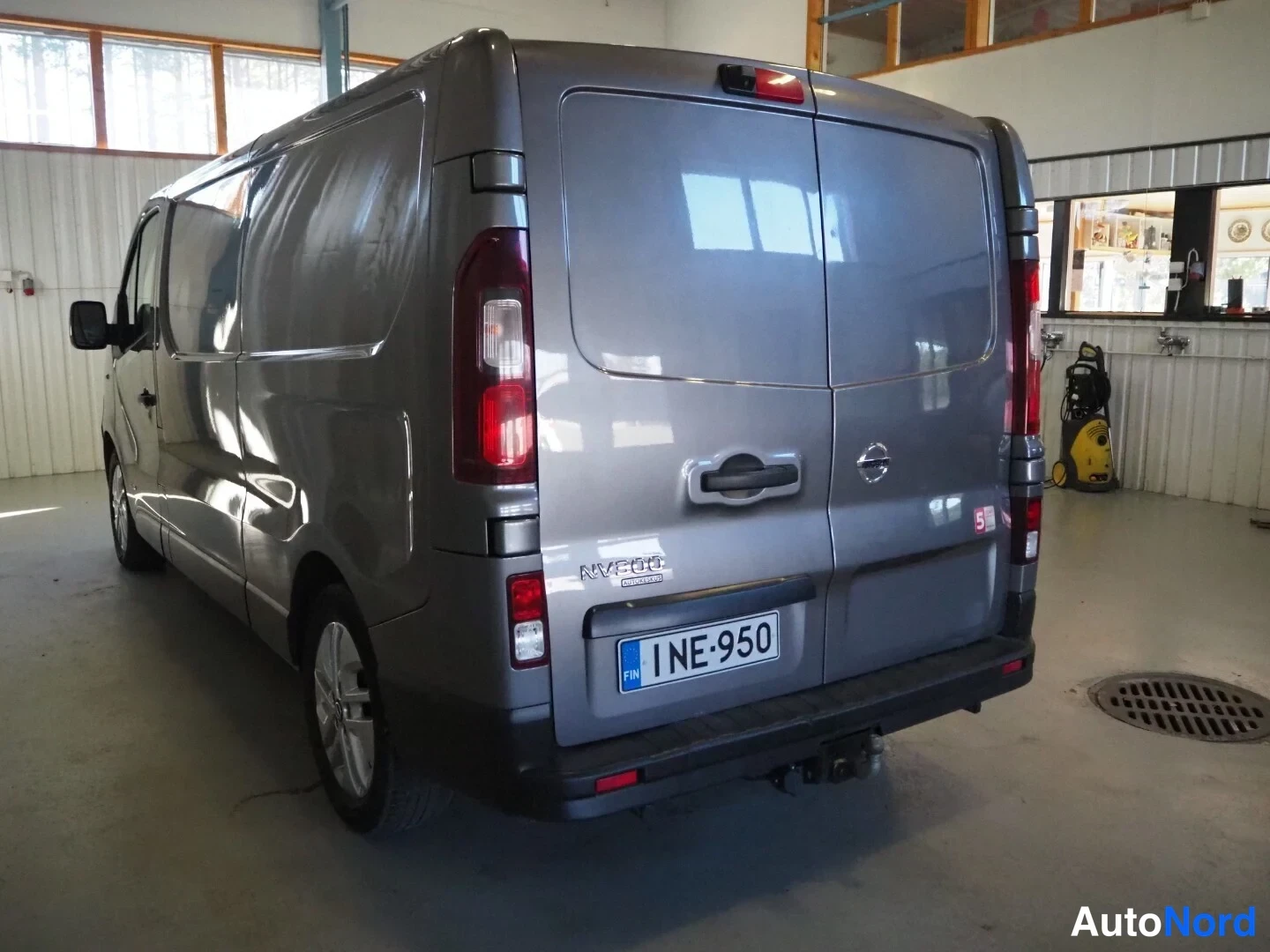 Takaviisto: Pakettiauton takakulma: harmaa Nissan NV300, rekisteritunnus, kaksoistakaluukut ja molemmat takavalot näkyvissä.