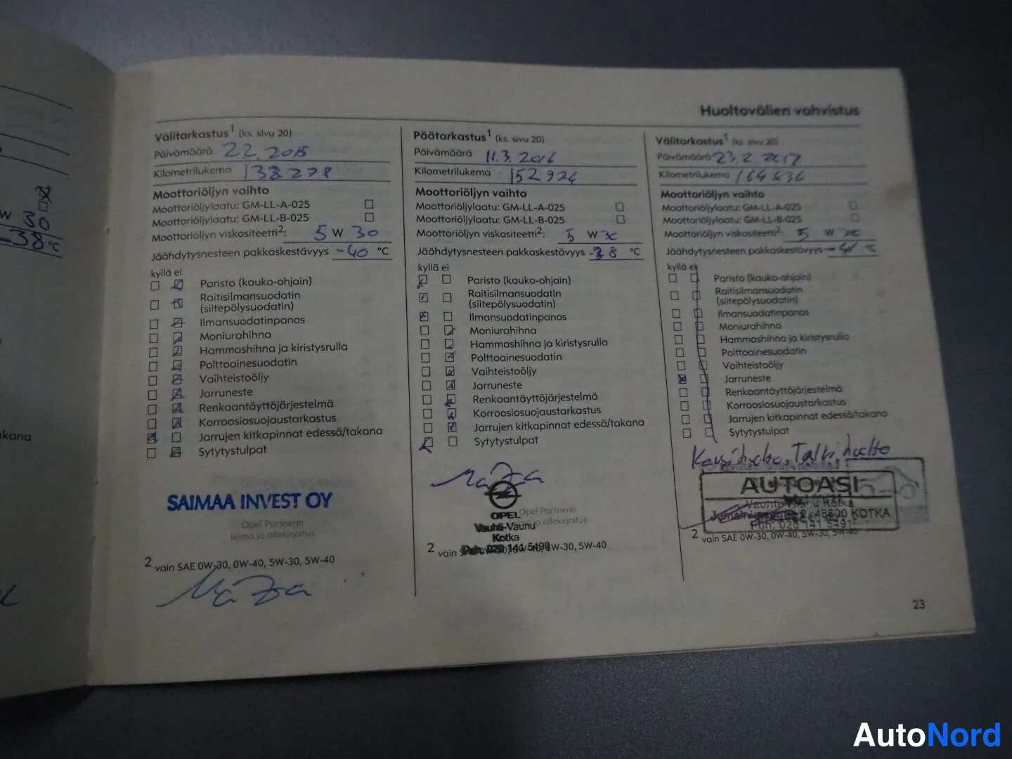 Asiakirja: Avattu huoltokirja, sivu 23, jossa näkyy kolme huoltotapausta vuodesta 2018. Oikealla AUTOASI:n väripiirrosleima.