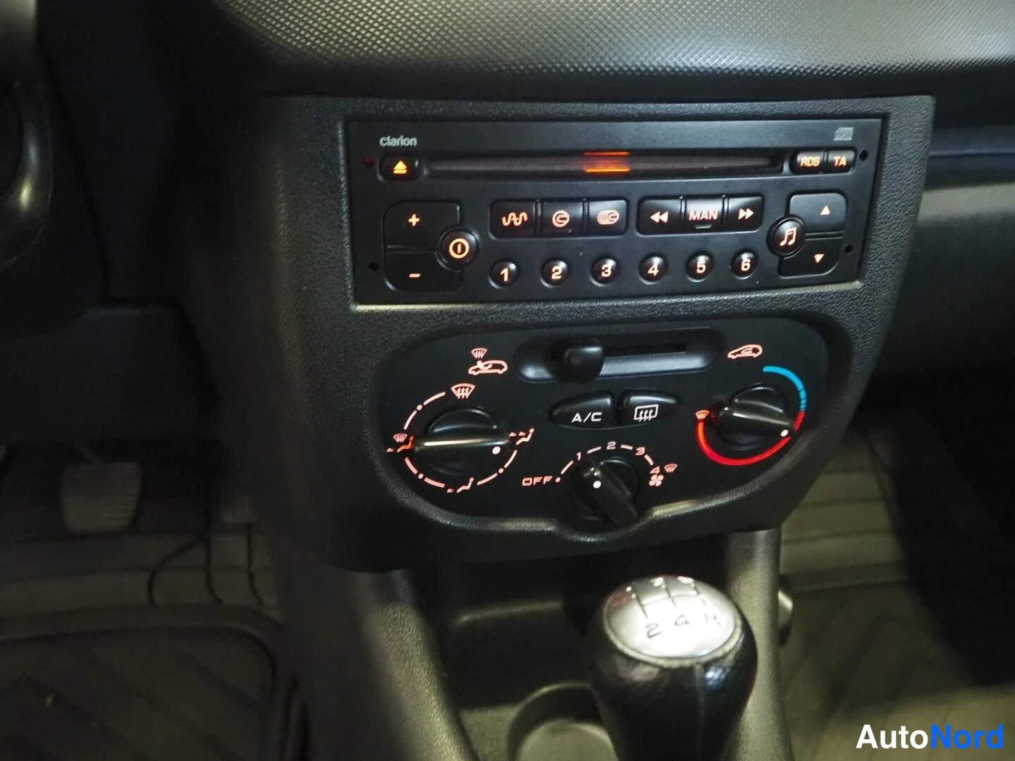 Muu: Peugeot 206:n keskikonsoli Clarion-radio-CD-soittimella, ilmastointipaneelilla A/C-napilla ja manuaalivaihteistokahvalla.