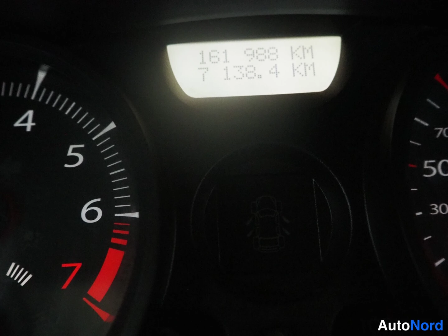 Yksityiskohta: Mittaristön kameranäyttö, jossa lukee 161 988 KM ja 7 138,4 KM; osa kaasutinmittarista ja nopeusmittarista näkyy.