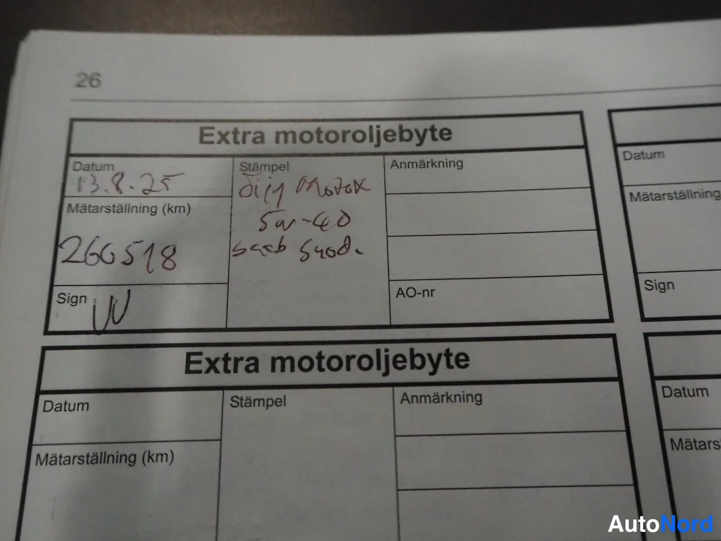 Asiakirja: Huoltokirjan sivu (sivu 26), jossa kaksi 'Extra motoroljebyte' -kenttää; ylemmäs täytetty: päiväys 13.8.25, matka-arvo 266518, leimaopas kirjoitettu käsialalla