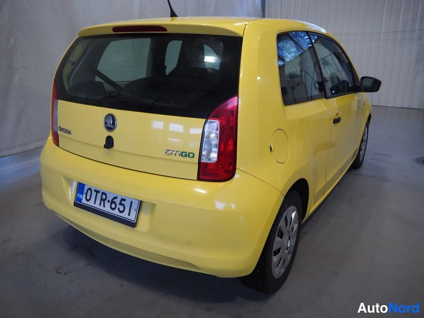 Takaviisto: Keltaisen Skoda Citigo -henkilöauton takaosan ja oikean kyljen kulmakuva, rekisterikilpi, takaluukussa CITIGO-teksti.