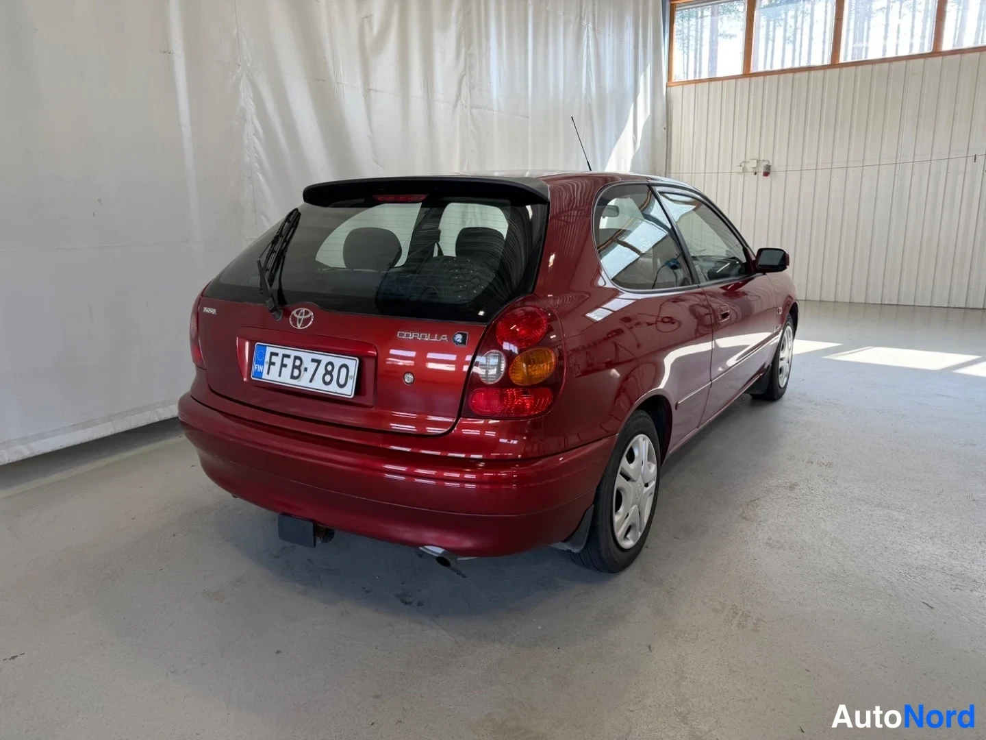 Takaviisto: Toyota Corolla -viistoperä takaa oikealta kuvattuna; punainen koripelti, takavalot ja rekisteritunnus näkyvät sisätiloissa.