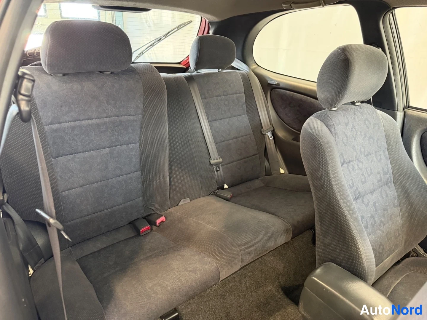 Takaistuimet: Rear seating area with three headrests and grey fabric upholstery.