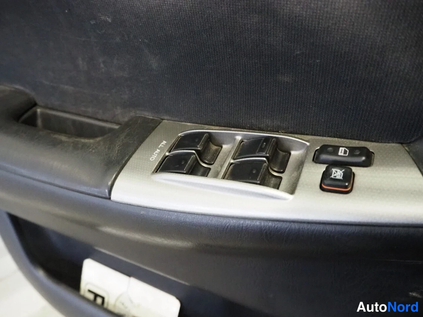 Muu: Ikkunanostimen kytkimet auton ovipanelissa; neljä nappia ja AUTO-merkintä.