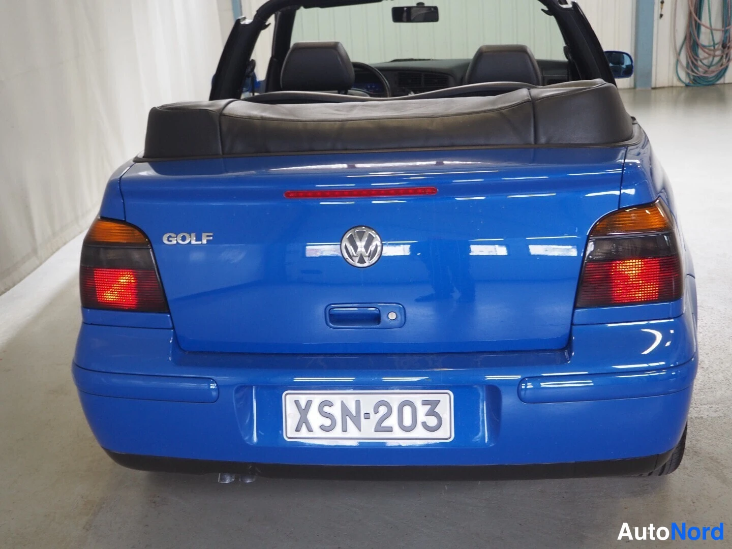 Takaa: Takaapäin kuvattu sininen Volkswagen Golf Cabriolet, jolla avokatto laskettuna ja rekisterikilpi.