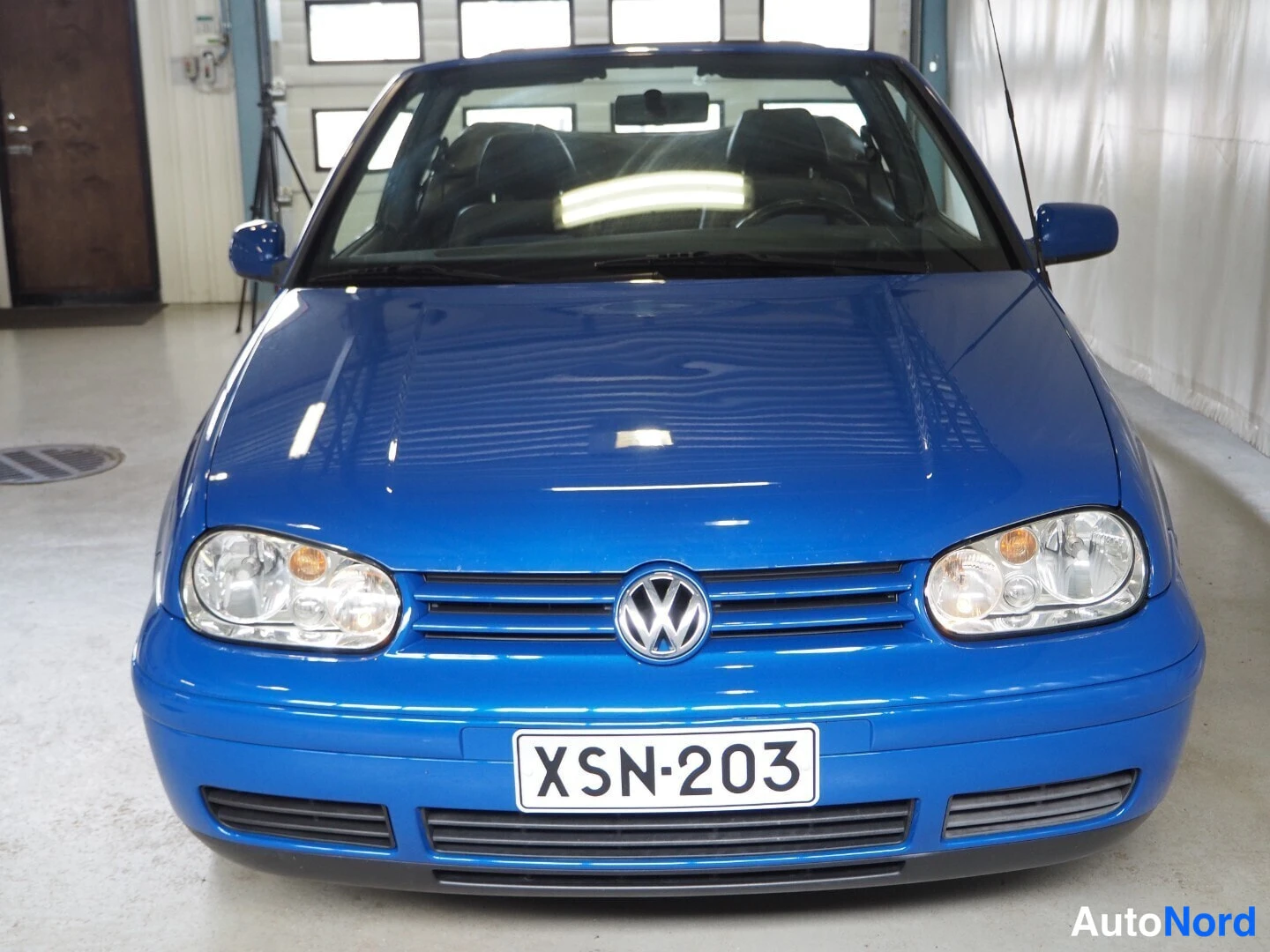 Edestä: Sininen auki auton edestä kuvattu Volkswagen Cabriolet, jossa avattu katto ja rekisterikilpi.