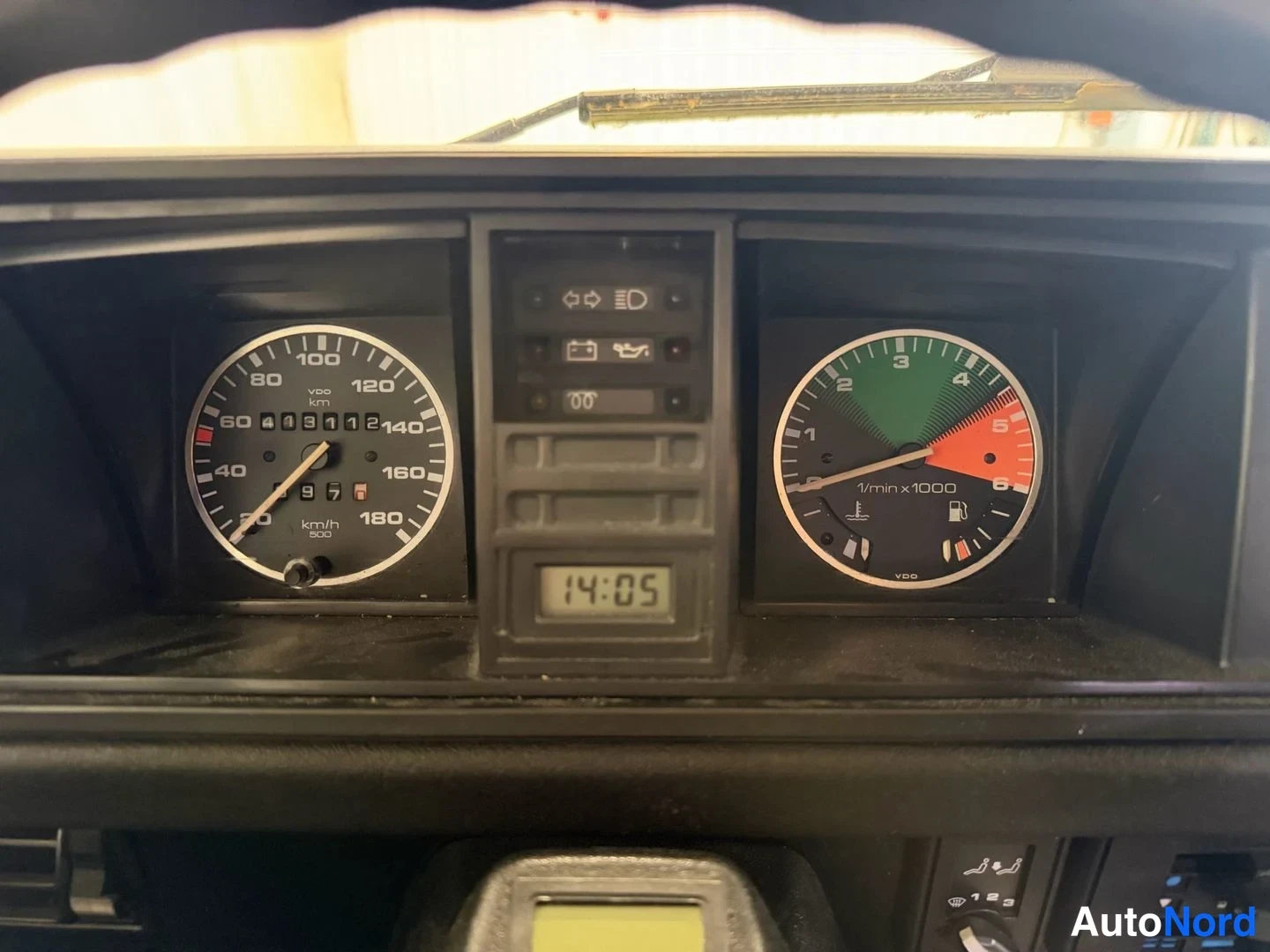 Sivulta: Mittaristön lähikuva: nopeusmittari asteikolla 20–180 km/h, kierrosmittari 1/min x1000, varoilmapaneeli ja kellonäyttö 14:05.