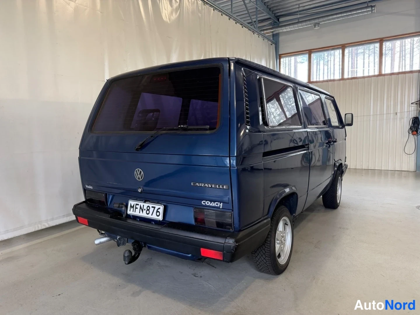 Takaviisto: Sininen pakettiauto takaviistöstä vasemmalta, takana CARAVELLE- ja Coach-tekstit sekä.