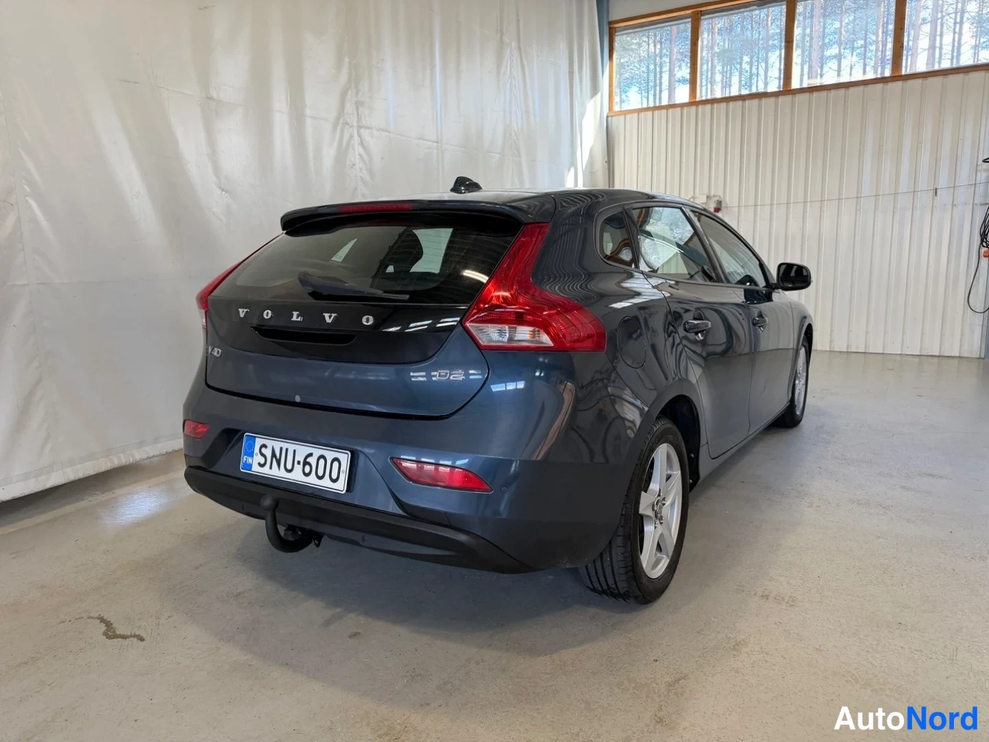 Takaviisto: Volvo V40 -henkilöauto takakulmasta, takavalot ja VOLVO-teksti takaluukussa, rekisterikilpi, vetokoukku näkyvissä.