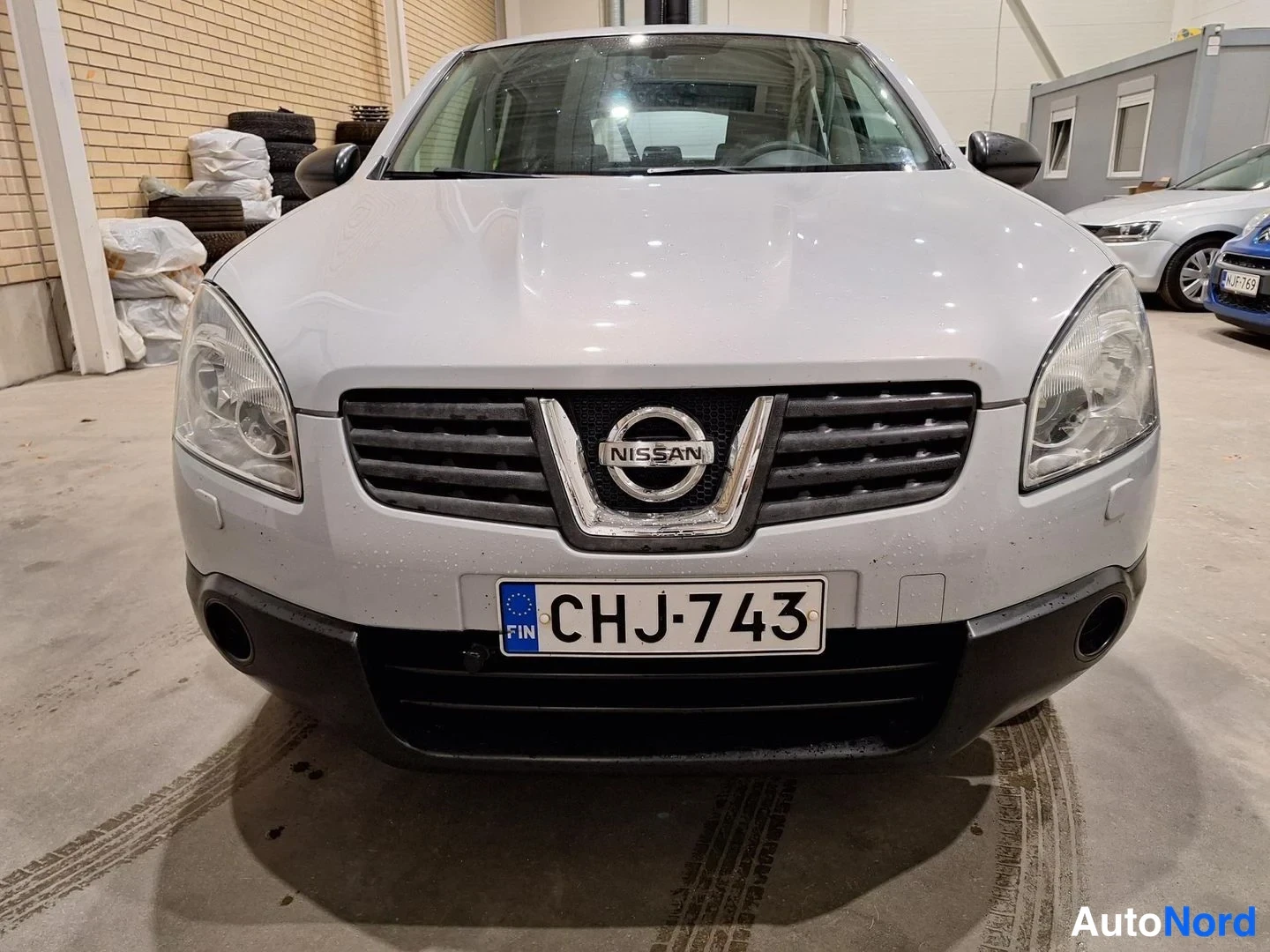 Edestä: Nissan Qashqain etunäkymä, rekisterikilpi ja Nissan-merkki etusäleikössä.