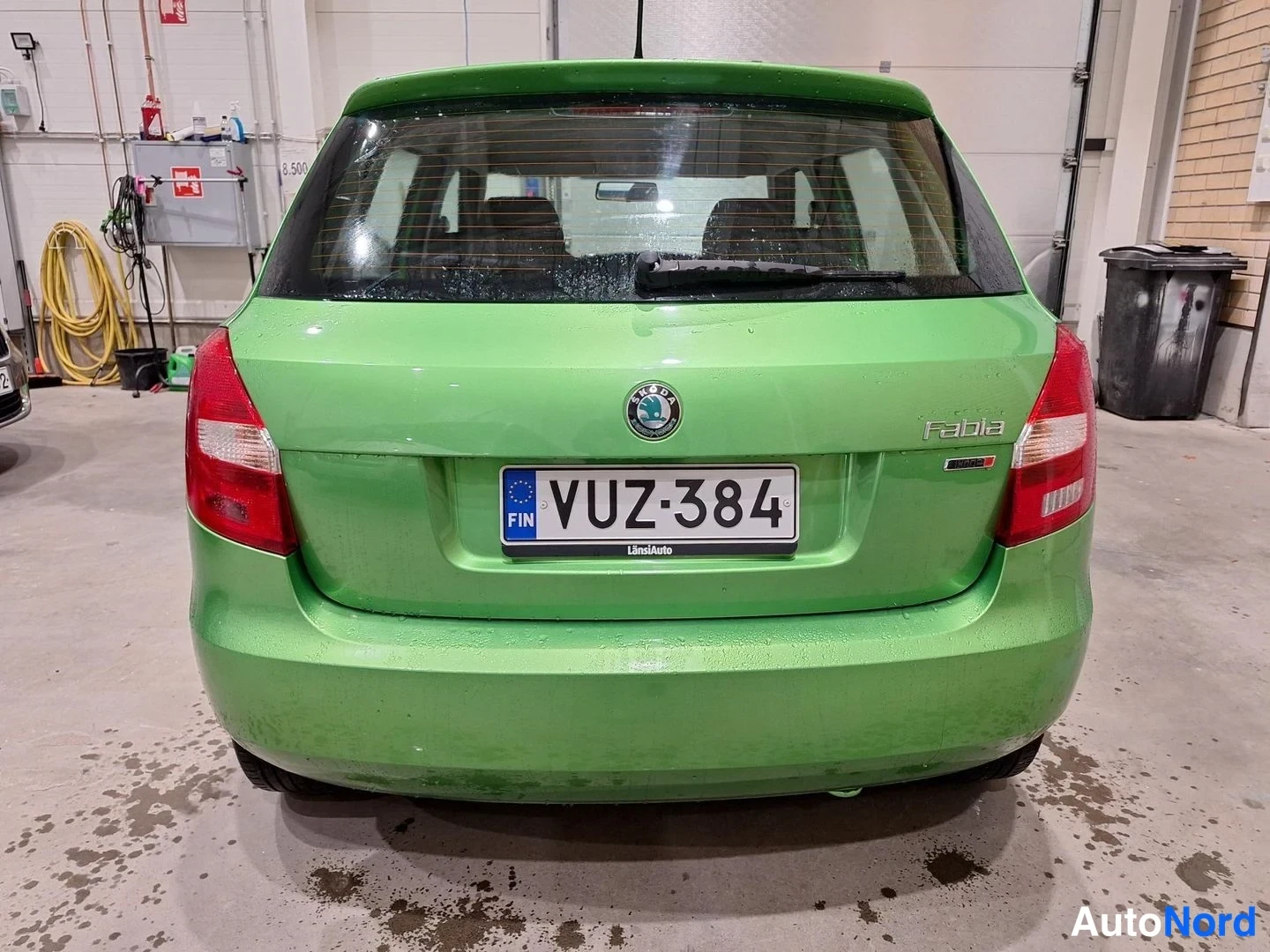 Takaa: Vihreän Skoda Fabian takaosa ja rekisterikilpi sisätiloissa.