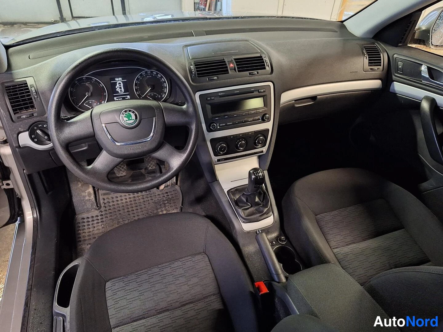 Muu: Ohjaamon kojelauta: Skoda-ohjauspyörä, mittaristo, radio ja manuaalivaihteen vaihdekeppi, tummat kangasistuimet.