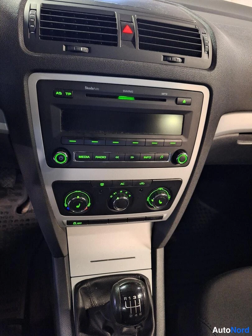 Sivulta: Keskikonsolin lähikuva: Skoda-radio ja kolme ilmastointisäädintä, AC-nappi ja 6-vaihteinen käsivaihtoe.