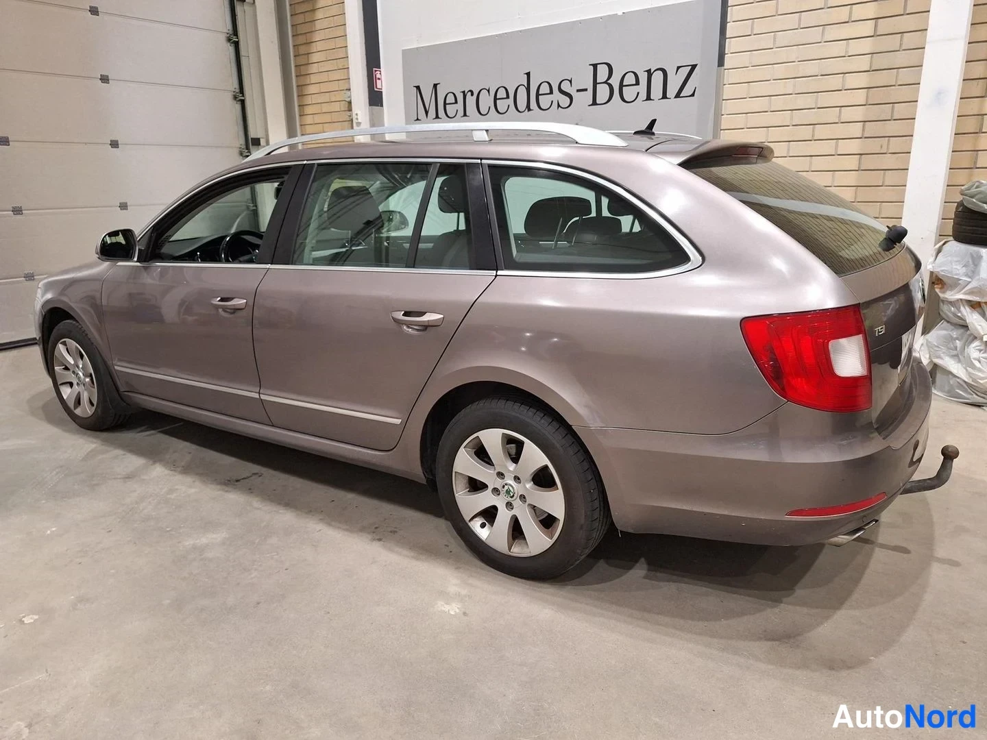 Takaviisto: Skoda Superb Combi sivulta takaa vasemmalta; ruskeanharmaa koriväri, kattotangot, TSI-merkintä takavalon vieressä.
