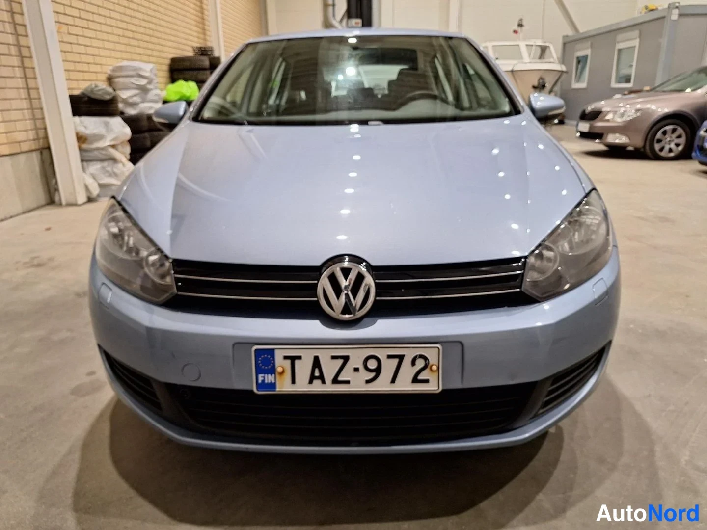 Edestä: Volkswagen Golf viistoperä suoraan edestä, vaaleansininen kori, rekisterikilpi.