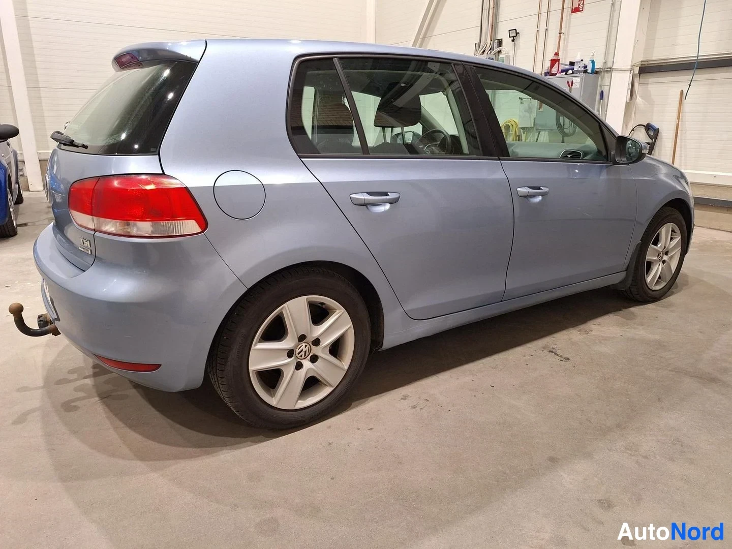 Takaviisto: Volkswagen Golf viistoperä takaviistosta vasemmalta, vaaleansininen kori ja vetokoukun kaula näkyvissä.