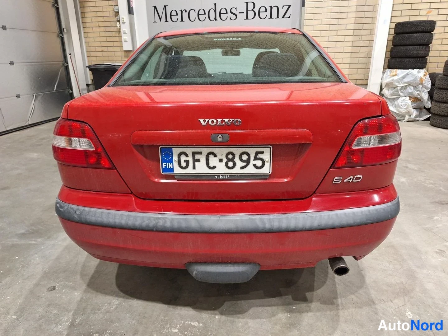 Takaa: Punaisen Volvo S40 -sedanin takanäkymä sisätiloissa, rekisterikilpi.