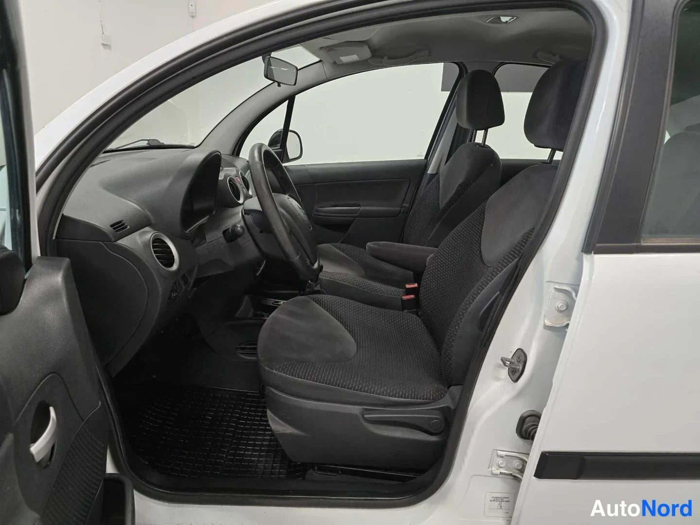 Sivulta: Kuljettajan puolen ovi auki Citroën C3:ssa: näkyy ohjaamo, eteen- ja takaistuimet sekä avattu ovi valkoisella korilla.