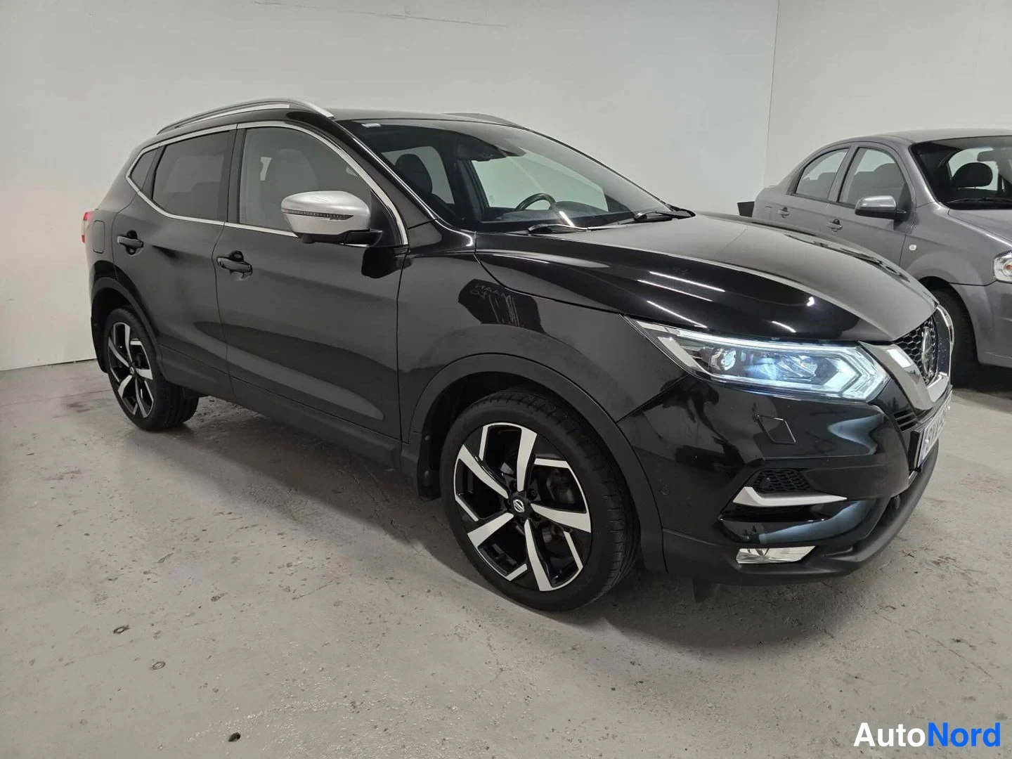 Etuviisto, nokka oikealle: Musta Nissan Qashqai -farmarityylinen katumaasturi kuvattu kolmeneljäsosakeulakulmasta etuposalla oikealla valkoisessa tilassa.