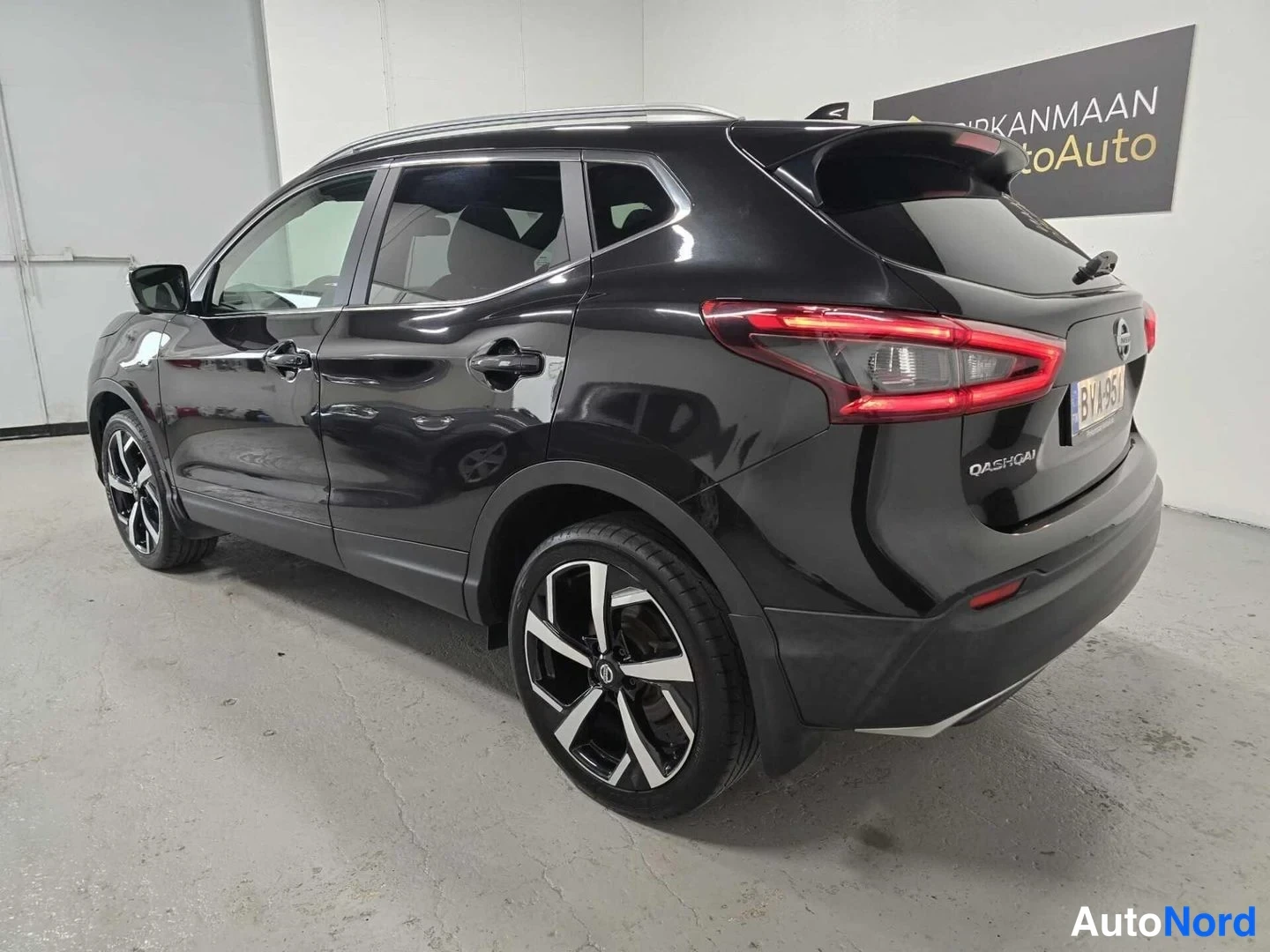 Takaviisto: Mustan Nissan Qashqai -maasturin takanurkkakuva vasemmalta, jossa näkyvät takavalot, Qashqai-tunnus ja rekisteritunnus.