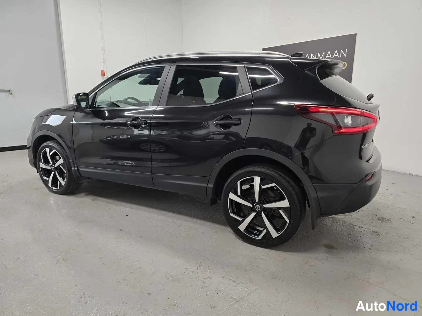 Takaviisto: Mustan Nissan Qashqai -maasturin takanurkkakuva vasemmalta, jossa näkyvät kylki, takavalot ja tummat kevytmetallivanteet.