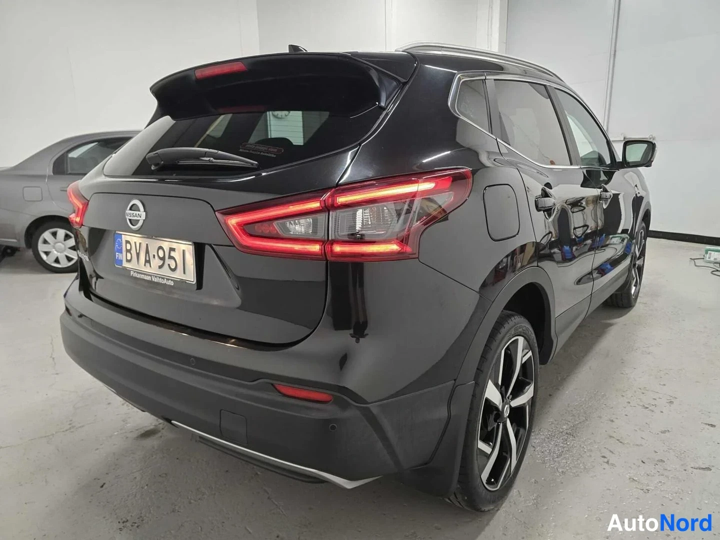 Takaa: Mustan Nissan Qashqai -maasturin takaosakuva suoraan takaa, jossa näkyvät Nissan-merkki, takavalot ja rekisteritunnus.