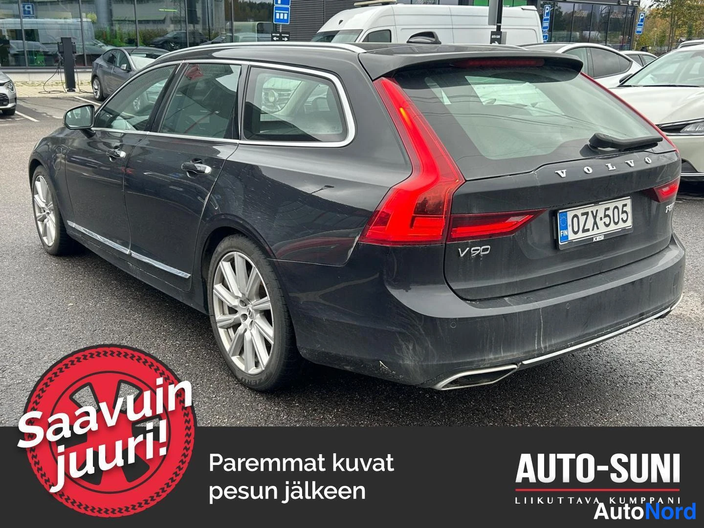 Takaviisto: Mustanharmaan Volvo V90:n taka­neljäsosan näkymä, takavalot ja V90-merkintä näkyvissä, kilpi.