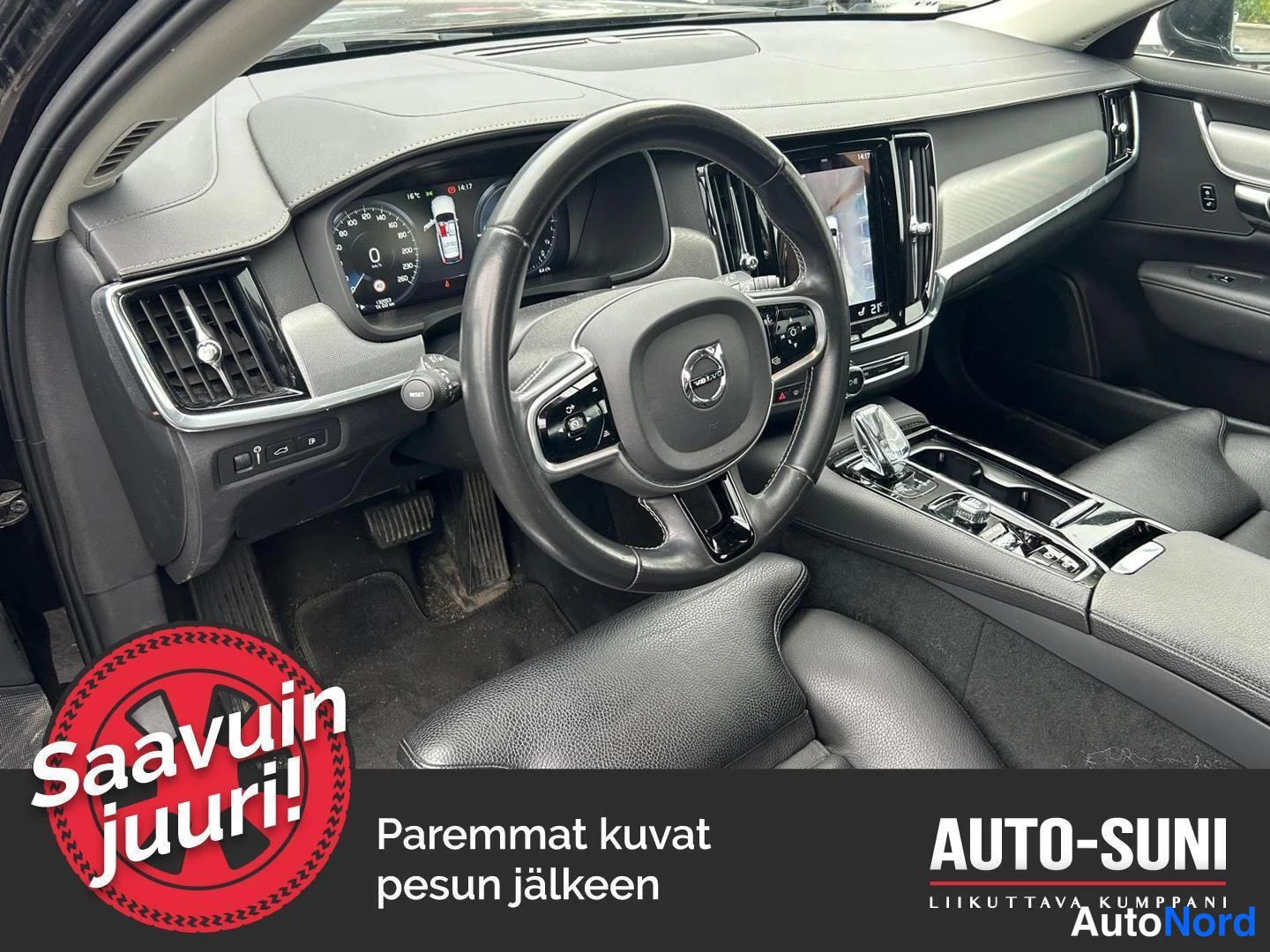 Muu: Volvo V90:n sisätilan yleiskuva: ohjauspyörä, mittaristo, keskikonsoli ja äänenvoimakkuuskonsoli, mustat penkit.