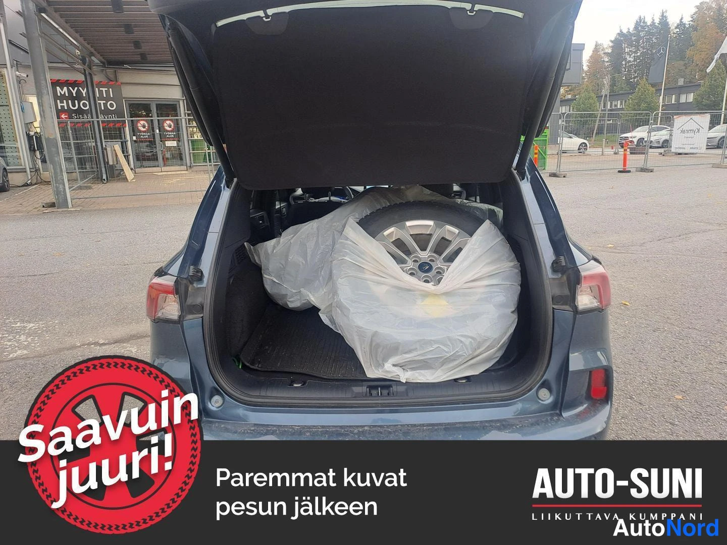Takaa: Auton takaosa takaluukku auki, takatilassa muovipussissa varapyörä vanteineen