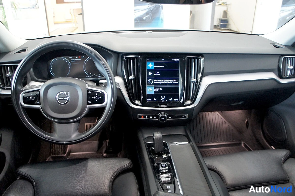 Sivulta: Volvo V60:n kuljettajan näkymä: ohjaustanko, digitaalinen mittaristo ja keskusnäyttö näkyvät auton sisältä etualalla.
